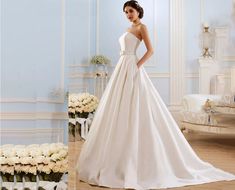 a woman in a white wedding dress standing next to flowers and a table with chairs