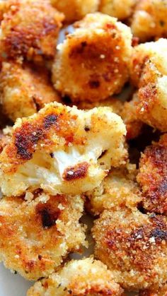 some fried food on a white plate with parmesan and seasoning sprinkles