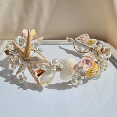 a bracelet with seashells, pearls and flowers on it sitting on a table