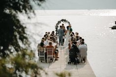 a group of people sitting on top of a pier next to the ocean with chairs around them