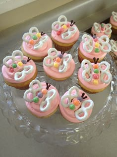 cupcakes decorated with pink frosting and white icing are on a glass plate