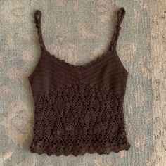 a brown crocheted tank top laying on the ground