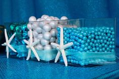 two vases filled with blue and white balls, starfish and seashells