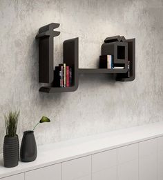 two bookshelves mounted on the wall above a white shelf with a potted plant next to it