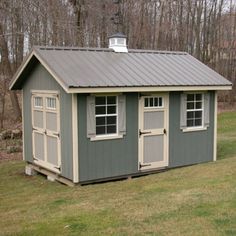 a small shed with two windows and a metal roof in the middle of a field