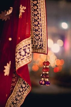 a close up view of the tassels and beads on a red cloth with lights in the background