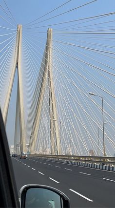 the view from inside a car looking at a bridge that is very tall and has many cables above it