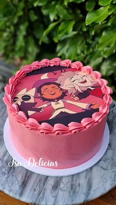 a pink cake with cartoon characters on it sitting on a marble table next to green leaves