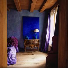 a room with blue walls and purple furniture in front of a painting on the wall