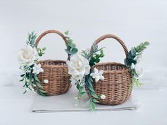 two wicker baskets with white flowers and greenery