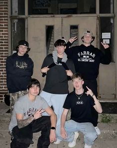 five young men posing for a photo in front of a building