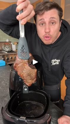 a man holding a meatloaf over an open air fryer