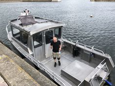 a man standing on top of a silver boat in the middle of a body of water