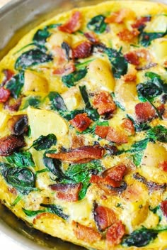 an omelet with bacon, spinach and cheese in a pan on a table