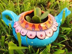 a potted plant is sitting in the grass on top of a blue teapot