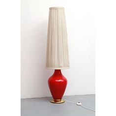 a red lamp sitting on top of a table next to a white wall and floor