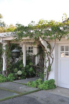 a house with white doors and vines growing on the side of it's roof