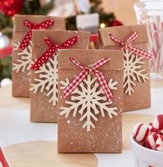 three brown bags with snowflakes on them sitting on a table next to candy canes