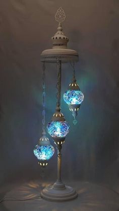 three blue and white lights hanging from a lamp post with chains attached to the sides