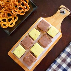 some food is sitting on a cutting board next to a plate with pretzels