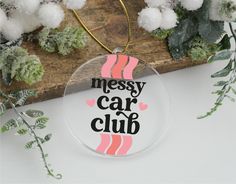 a glass ornament with the words messy car club on it next to some plants