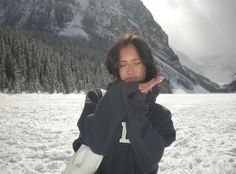 a woman is standing in the snow with her eyes closed and hands clasped to her face