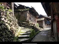 an alley way with stone steps and wooden buildings