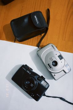 two cameras sitting on top of a table next to each other