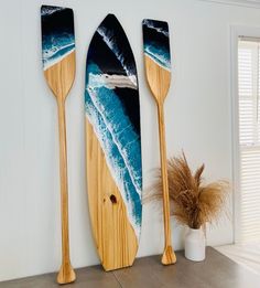 two wooden paddles are hanging on the wall next to a potted plant and vase