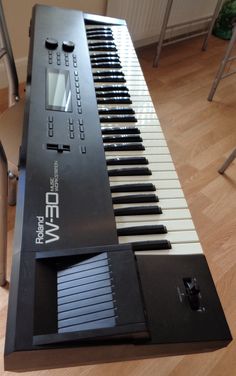 an electronic keyboard sitting on top of a hard wood floor