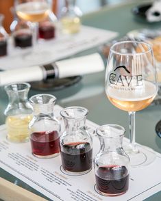 a table topped with wine glasses filled with different types of liquid and liquids in beakers