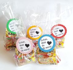 four bags filled with different types of candies in plastic wrappers on top of a white surface