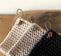 two crocheted bags hanging from hooks on a wooden surface