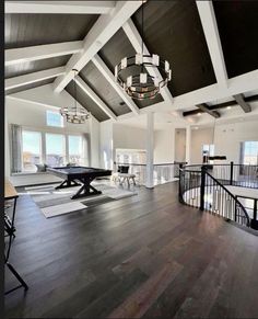 a large open living room with hardwood floors and white walls, chandelier hanging from the ceiling