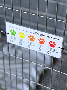 a sign that is on the side of a metal cage with paw prints and colors