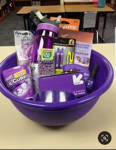 a purple bowl filled with lots of items on top of a table in a library