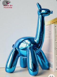 a blue balloon dog sitting next to a book