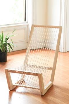 a wooden chair sitting on top of a hard wood floor next to a potted plant