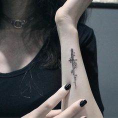 a woman's arm with a cross tattoo on the left side of her wrist