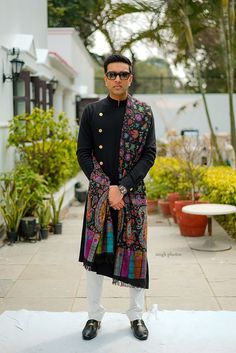 a man standing in front of some potted plants wearing sunglasses and a colorful scarf