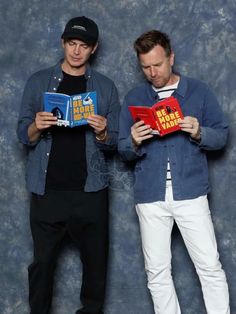 two men standing next to each other holding books