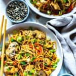 two bowls filled with noodles and vegetables next to chopsticks on a white table