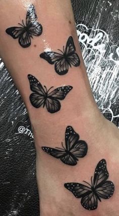 a woman's foot with black butterflies tattooed on the side of her leg,