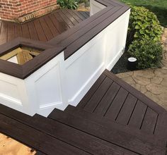 an open window on the side of a wooden deck in front of a brick building