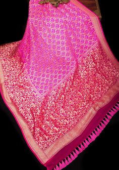 This custom-designed saree is beautified with the Bandhej work of Gujarat on a resplendent pure silk georgette saree from Banaras! Set in striking Pink, a close look at the Shikaargah pattern with an all-over Border of peacock, parrots,deer & Elephant is sure to wow you! Thousands of hand-plucked and resist-tied dots make it a piece of art! The pallu is equally resplendent with stunning motifs.  The fabric is pure georgette that is processed from pure silk yarns and woven to beauty, The saree is Silk Tassels, Georgette Saree, Silk Yarn, Shades Of Pink, Georgette Sarees, Blouse Fabric, Saree Blouse, Pure Silk, Womens Clothing Tops