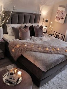 a large bed sitting in a bedroom next to a night stand with candles on it