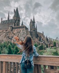 a woman standing on a bridge looking at hogwarts castle