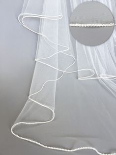 a white veil with beaded edge on a gray background and a round hole in the middle