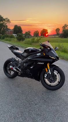 the motorcycle is parked on the side of the road in front of the setting sun