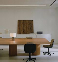 a large wooden table with two chairs and a lamp on the end in an empty room